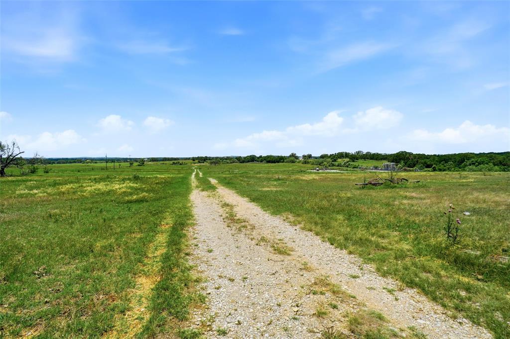 2186 Gilliland Road Springtown, TX 76082 - Photo 7 of 25 Expansive open field featuring a gravel path, mature trees, and natural grassland