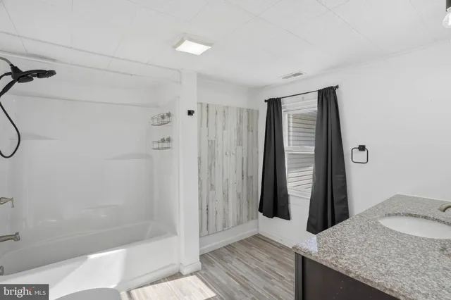 a bathroom with a granite countertop sink and shower