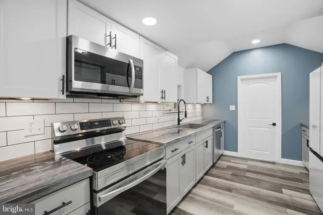 a kitchen with stainless steel appliances granite countertop a sink and a stove