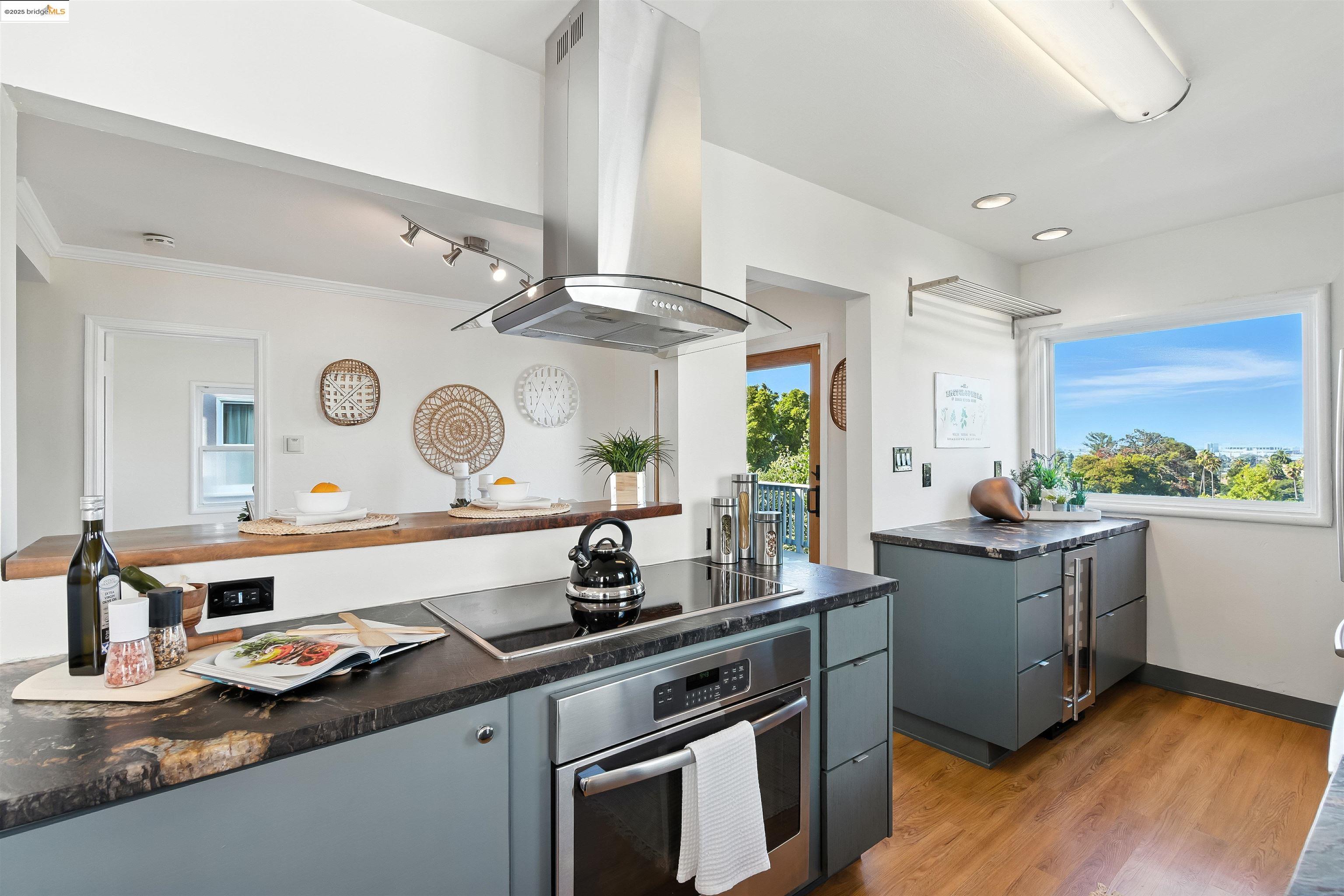 6623 Outlook Avenue Oakland, CA 94605 - Photo 13 of 38 Kitchen with island range hood, light wood-style floors, oven, black electric stovetop, and gray cabinetry