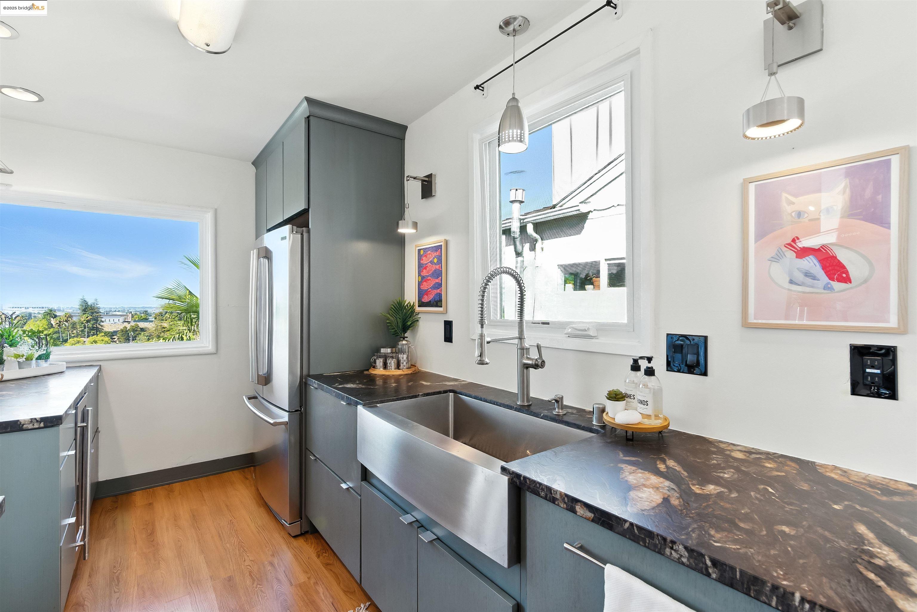 6623 Outlook Avenue Oakland, CA 94605 - Photo 14 of 38 Kitchen featuring gray cabinetry, light wood finished floors, pendant lighting, freestanding refrigerator, and dark stone countertops