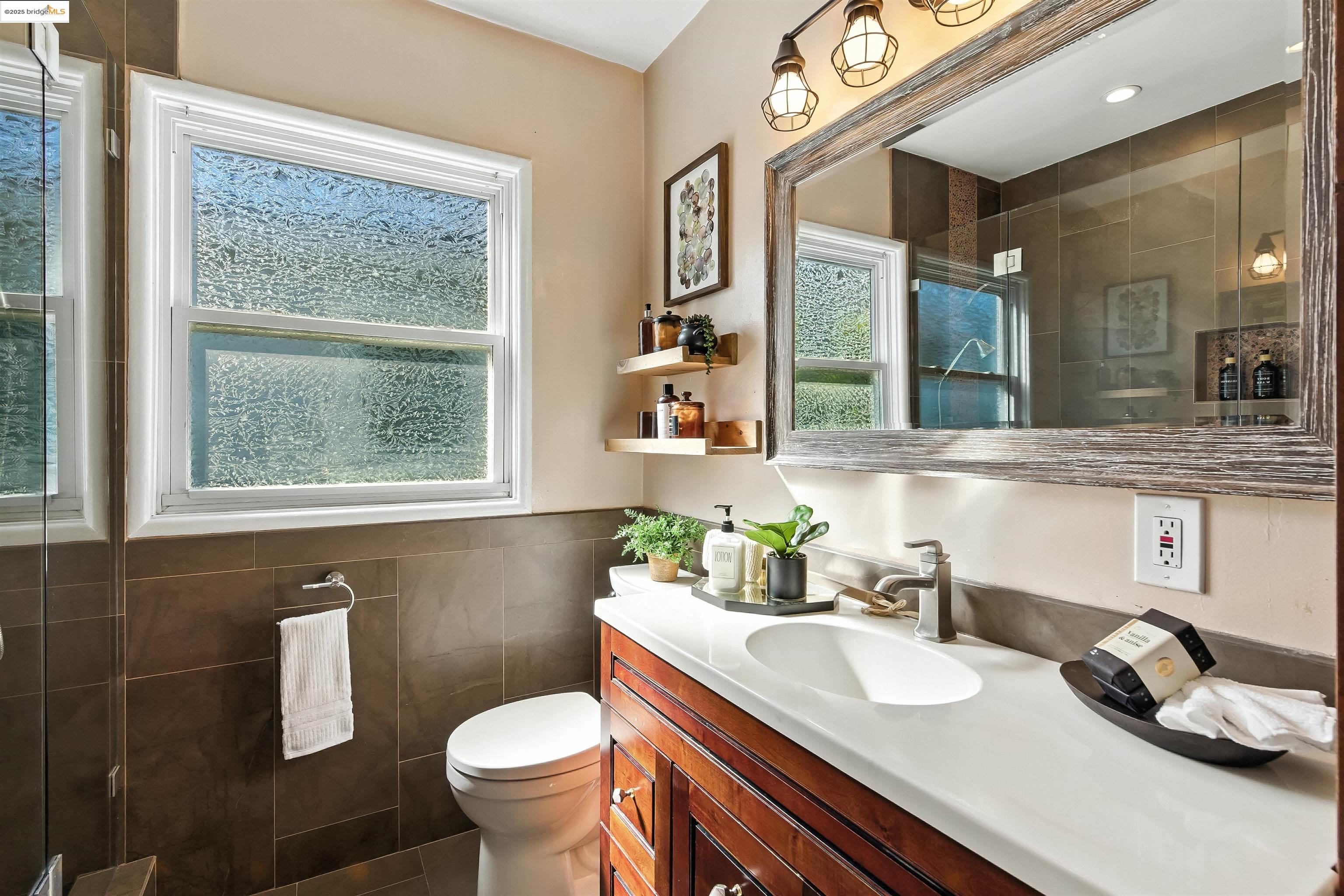 6623 Outlook Avenue Oakland, CA 94605 - Photo 21 of 38 Bathroom featuring a shower stall, vanity, tile walls, dark tile patterned floors, and a wainscoted wall