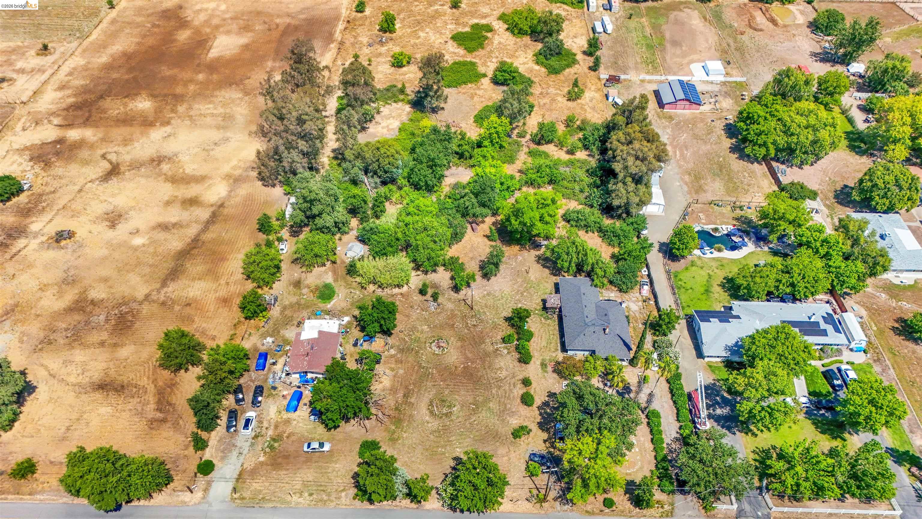 7750 Locke Road Vacaville, CA 95688 - Photo 5 of 23 Expansive aerial property featuring a main residence with a dark shingle roof, surrounded by mature trees