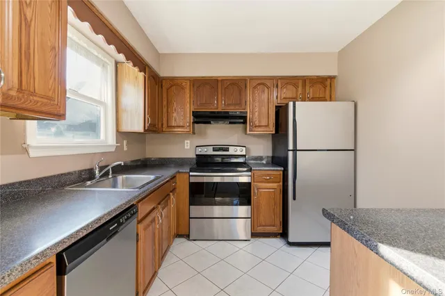 a kitchen with granite countertop a refrigerator stove and sink