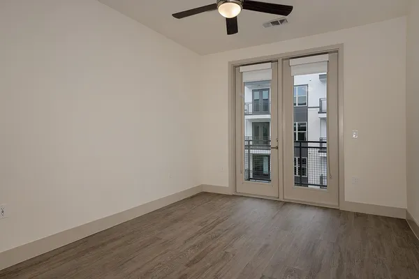 an empty room with wooden floor chandelier fan and windows