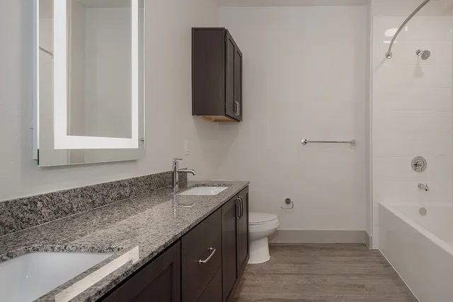 a bathroom with a granite countertop sink toilet and bathtub