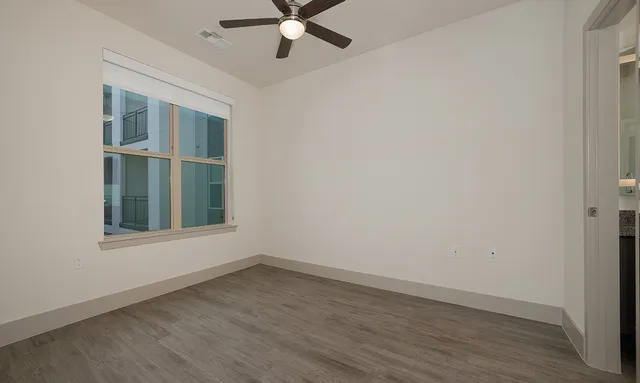 an empty room with a window and a fan
