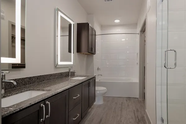 a bathroom with a granite countertop sink mirror and a bathtub