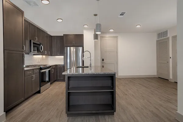 a kitchen with stainless steel appliances kitchen island granite countertop a stove a sink and a refrigerator