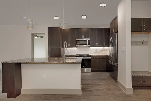 a large kitchen with cabinets wooden floor and stainless steel appliances