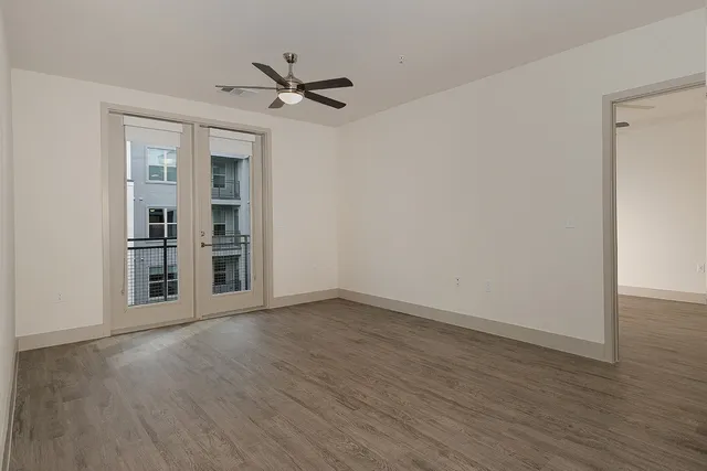 a view of an empty room with a window and wooden floor