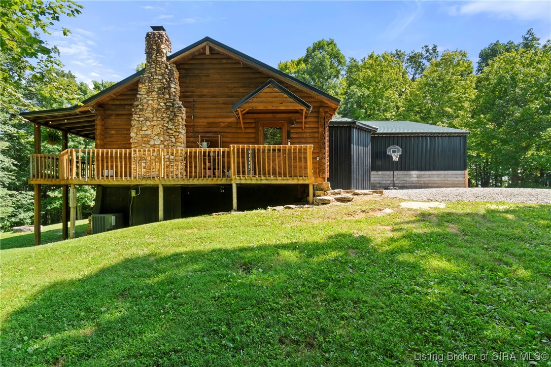 Daytime Deck and Chimney View – Natural wood deck and striking stone chimney set against a lush green yard.