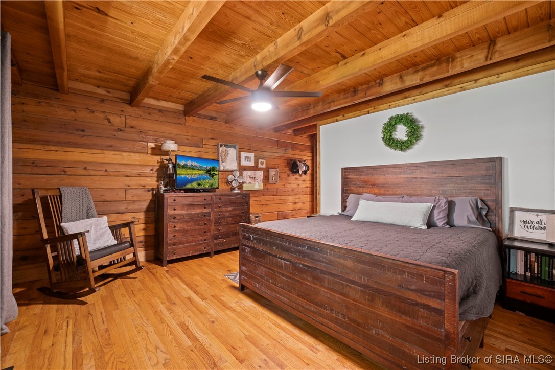 3895 Utz Road Northeast Georgetown, IN 47122 - Photo 19 of 70 Primary Bedroom – Warm wood walls and ceiling beams create a cozy retreat, complemented by hardwood flooring and ample space for a king-sized bed.