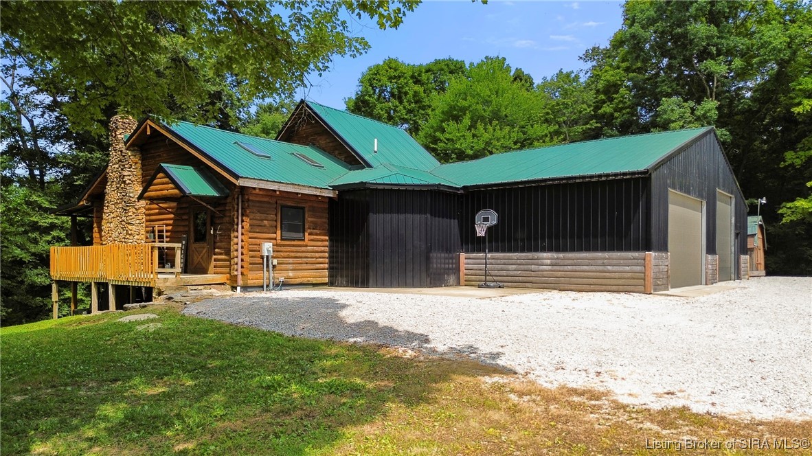 3895 Utz Road Northeast Georgetown, IN 47122 - Photo 2 of 70 Front Exterior View – Rustic log cabin style home with green metal roof, stone chimney, and attached oversized garage.