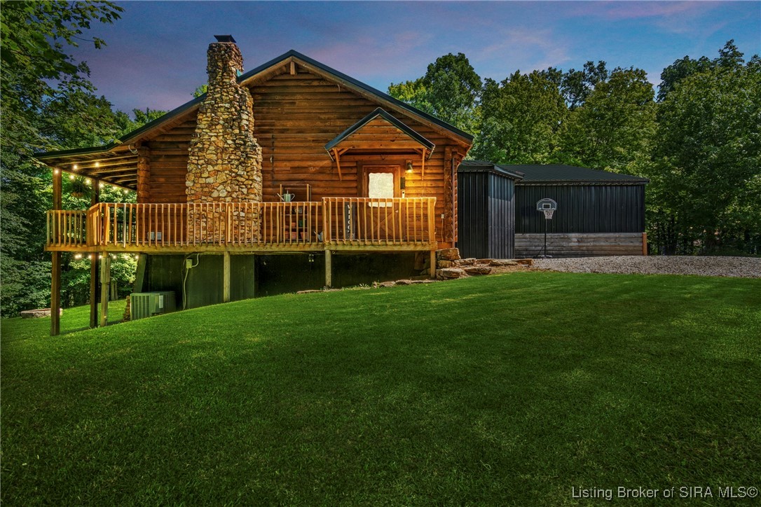 3895 Utz Road Northeast Georgetown, IN 47122 - Photo 53 of 70 Evening Deck and Chimney View – Warm exterior lighting illuminates the wrap-around deck and impressive stone chimney.