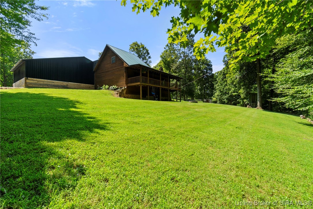 3895 Utz Road Northeast Georgetown, IN 47122 - Photo 56 of 70 Back Lawn and Home – Wide grassy yard behind home with wrap-around porch and wooded backdrop.