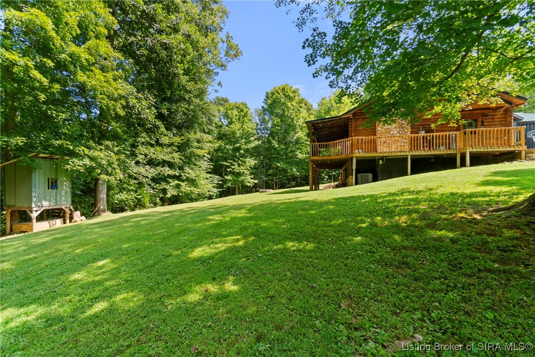 3895 Utz Road Northeast Georgetown, IN 47122 - Photo 57 of 70 Rear Deck and Stone Chimney View – Wrap-around deck with stone chimney overlooking lush green space.