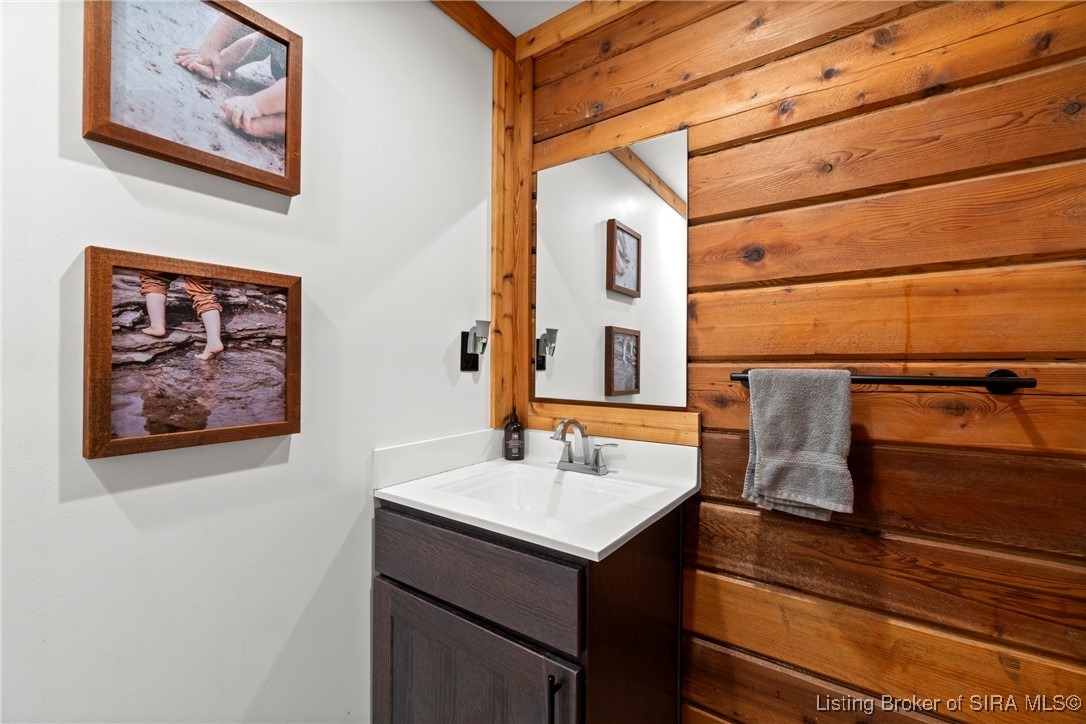 3895 Utz Road Northeast Georgetown, IN 47122 - Photo 64 of 70 Half-bath sink area with wood-paneled wall, mirror, towel bar, and modern fixtures.
