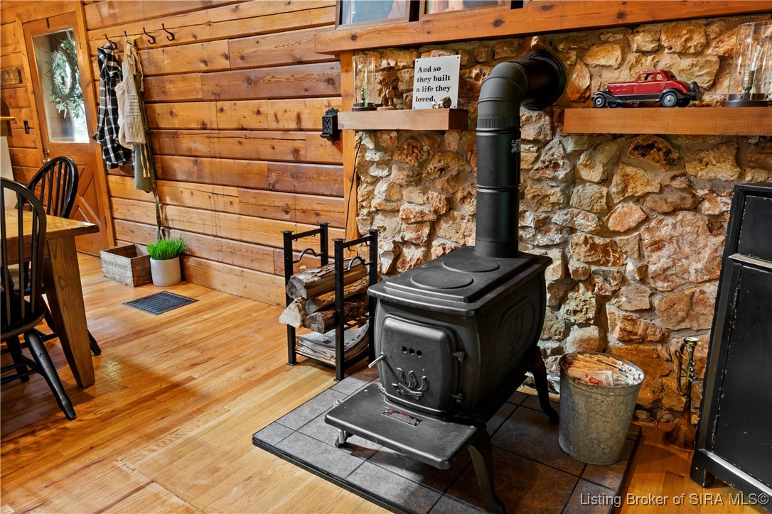 3895 Utz Road Northeast Georgetown, IN 47122 - Photo 8 of 70 Rustic wood stove set against a stone accent wall with firewood storage and decorative shelving.