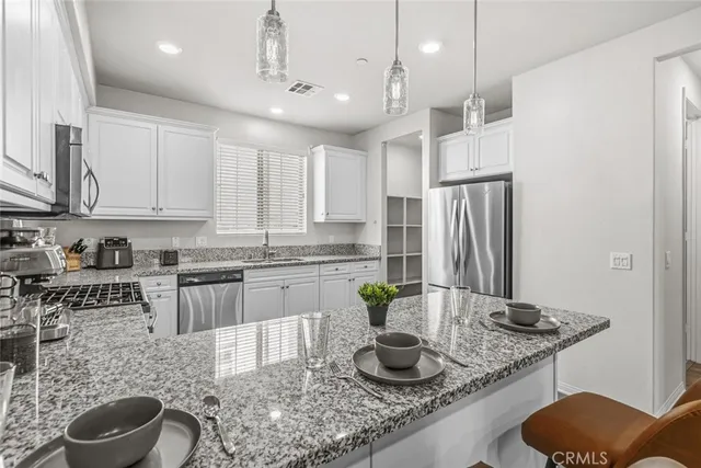 a kitchen with stainless steel appliances granite countertop a sink a stove and a wooden floors