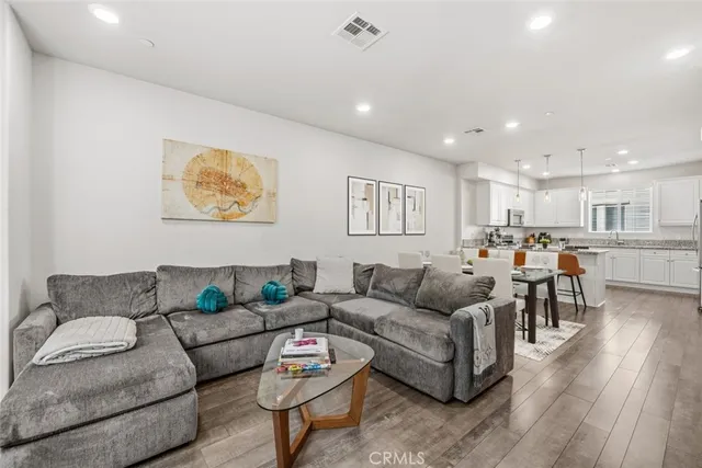 a living room with furniture kitchen view and a wooden floor