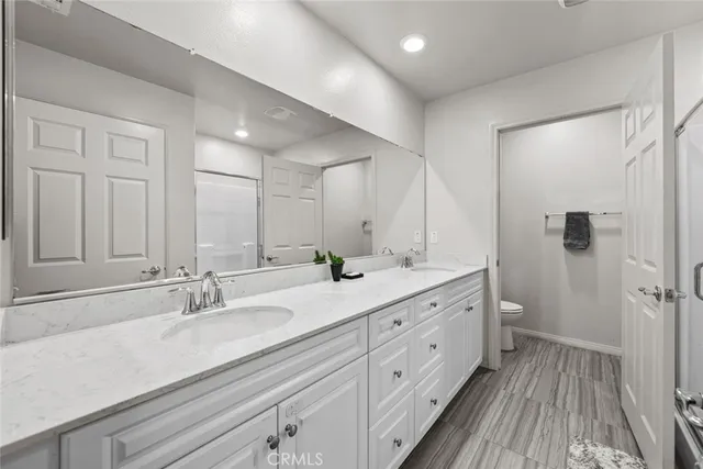a spacious bathroom with a double vanity sink a mirror and a shower