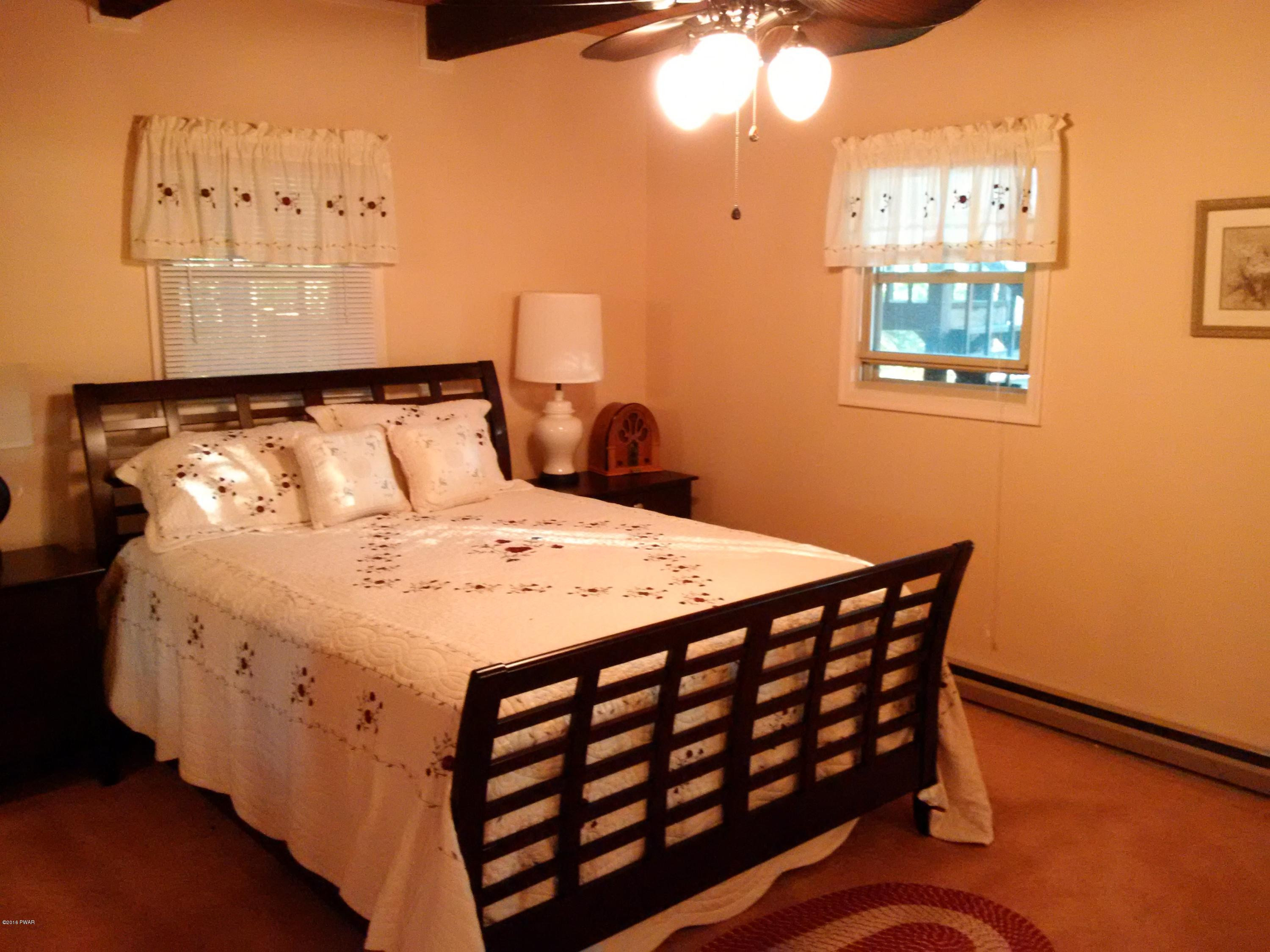 3016 Northgate Road Lake Ariel, PA 18436 - Photo 58 of 58 a bed sitting in a bedroom next to a lamp with wooden floor