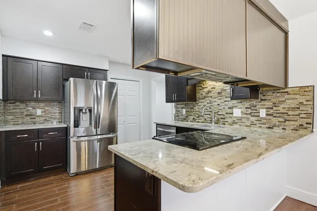a kitchen with kitchen island granite countertop a sink stove and refrigerator