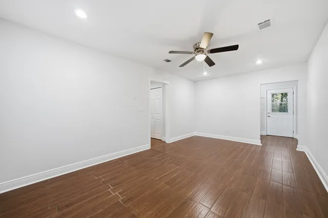 an empty room with wooden floor and windows