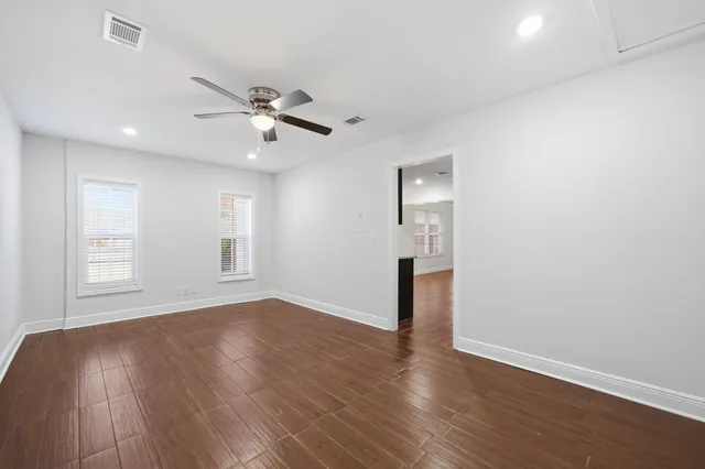 a view of empty room with wooden floor and fan