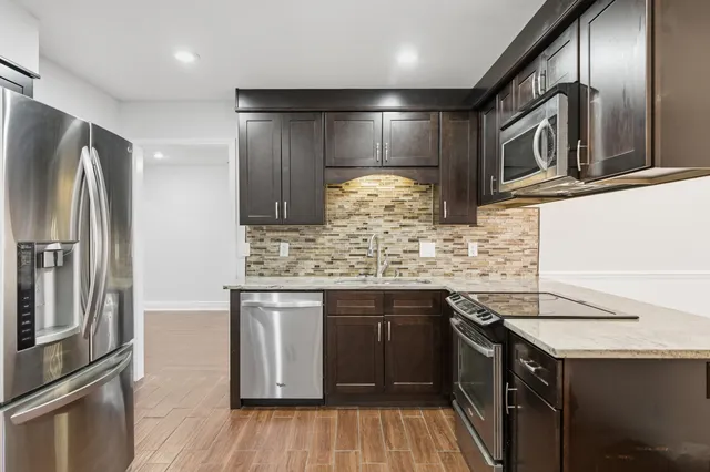 a kitchen with stainless steel appliances granite countertop a sink and a refrigerator