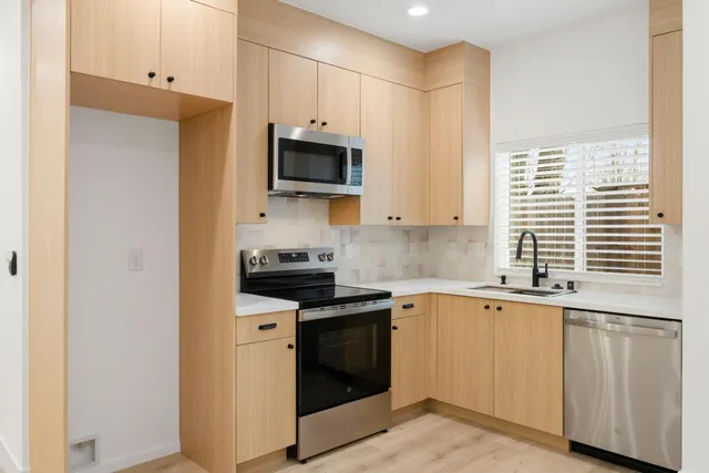 a kitchen with stainless steel appliances granite countertop a stove a sink and a microwave