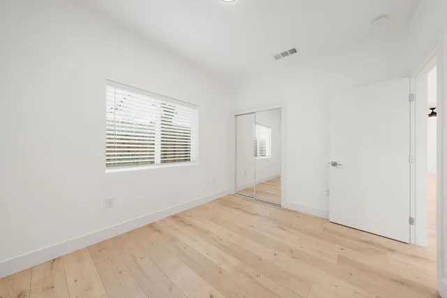 an empty room with wooden floor and windows