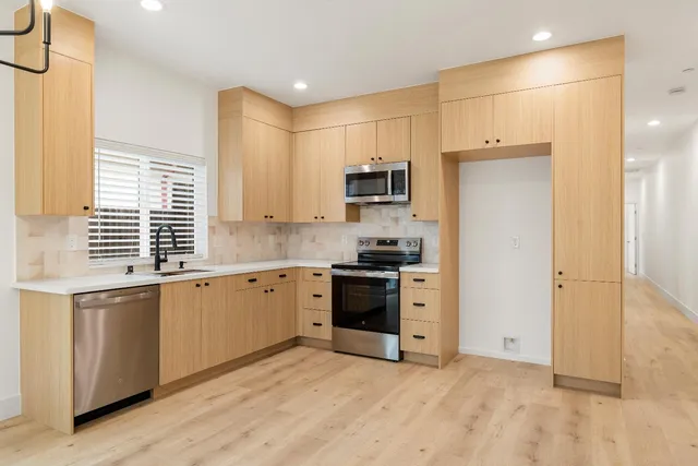 a kitchen with stainless steel appliances a stove a sink and a refrigerator