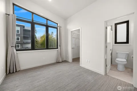 a view of a hallway with wooden floor and a bathroom