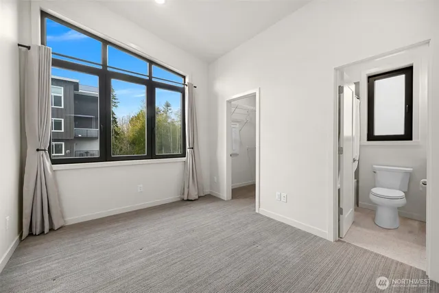 a view of a hallway with wooden floor and a bathroom