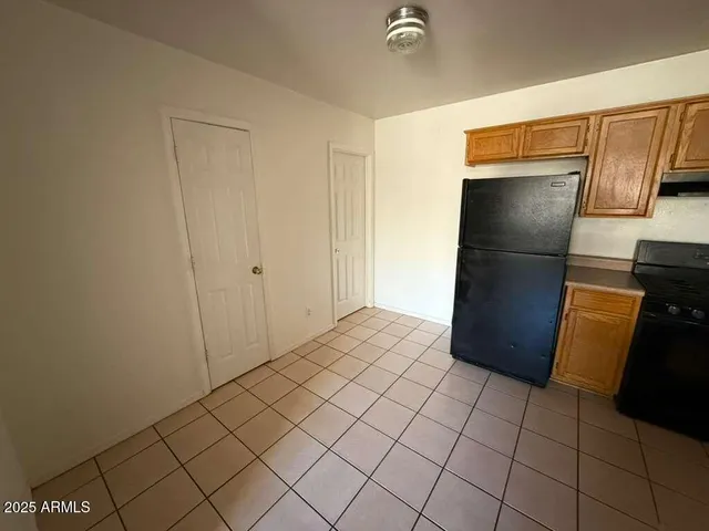 a view of a refrigerator in kitchen and an empty room