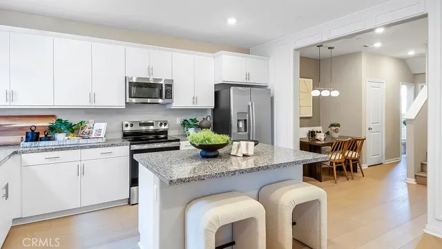 a kitchen with stainless steel appliances granite countertop a table chairs refrigerator and microwave