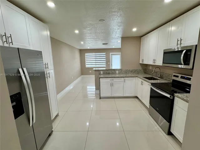 a kitchen with stainless steel appliances granite countertop a refrigerator a sink a stove top oven and a refrigerator