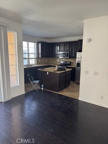 a kitchen with stainless steel appliances granite countertop a stove top oven a sink dishwasher and a refrigerator with wooden floor