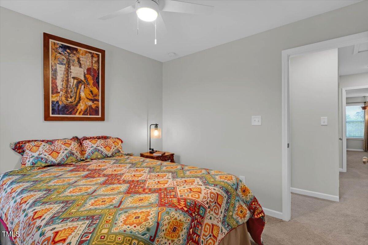 9834 Bitter Melon Drive Angier, NC 27501 - Photo 19 of 29 a bedroom with a large bed and a chandelier