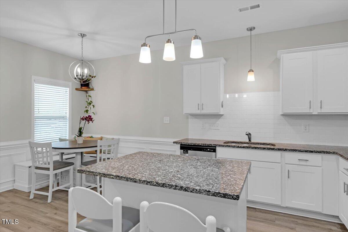 9834 Bitter Melon Drive Angier, NC 27501 - Photo 9 of 29 a kitchen with white cabinets and chandelier