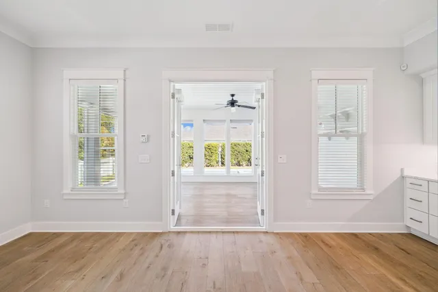 a view of an empty room with a window and wooden floor