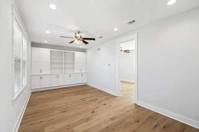 a view of empty room with wooden floor and fan