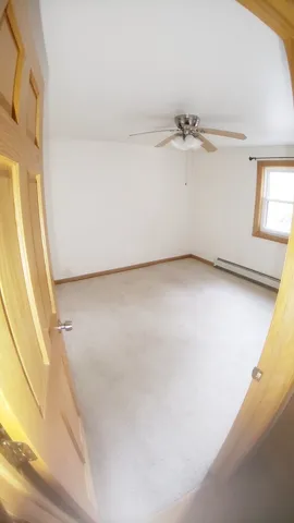 a view of a room with a ceiling fan and wooden floor