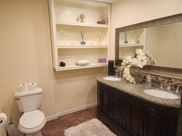 a bathroom with a granite countertop sink a toilet and a mirror
