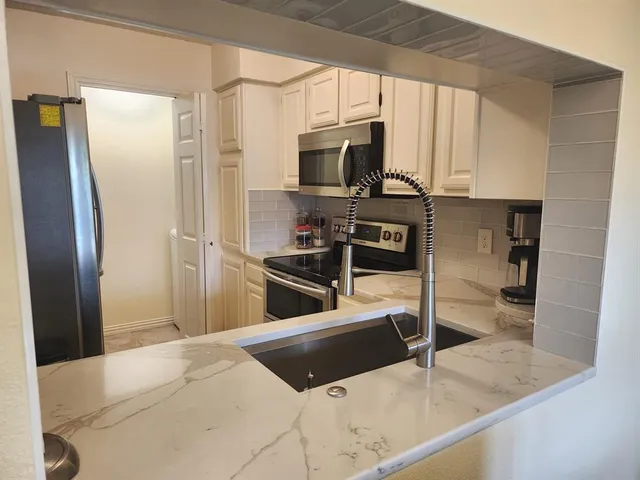 a kitchen with stainless steel appliances granite countertop a refrigerator a stove and a sink