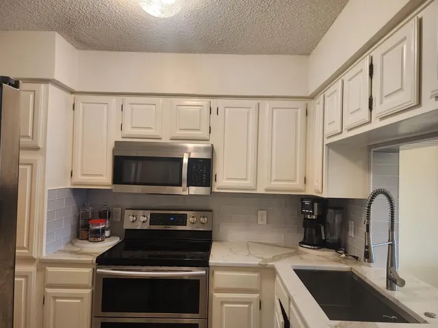 a kitchen with stainless steel appliances granite countertop a stove a microwave and a refrigerator