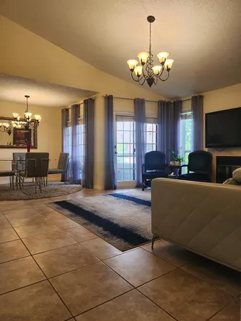 a living room with furniture a chandelier and a flat screen tv