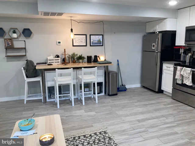 a living room with stainless steel appliances furniture a rug and a view of kitchen
